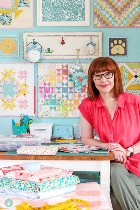 In Search of my Sewing Mojo and Other Tales of Summer by popular sewing blog, Diary of a Quilter: image of a woman sitting on a chair and leaning on a table that is covered with sewing supplies and quilting fabric.