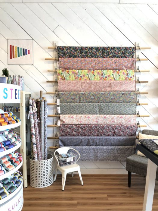 Pintuck & Purl - Modern Fabric and Knitting Shop by popular quilting blog, Diary of a Quilter: image of fabric yards hanging on a wall inside Pintuck and Purl.