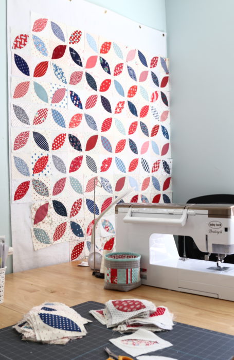 In Search of my Sewing Mojo and Other Tales of Summer by popular sewing blog, Diary of a Quilter: image of a sewing room with a white sewing machine on a table and red, white and blue block quilt on the wall.