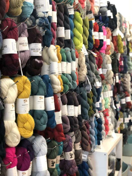 Pintuck & Purl - Modern Fabric and Knitting Shop by popular quilting blog, Diary of a Quilter: image of various colors of yarn hanging on display pegs inside Pintuck and Purl.