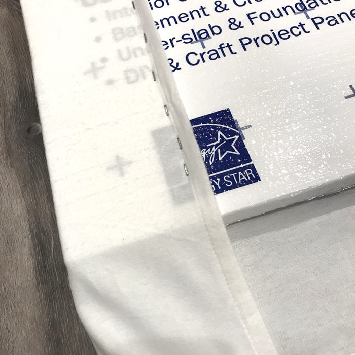 How to Build a Quilt Design Wall by Christa Watson by popular quilting blog, Diary of a Quilter: image of a king size white flannel sheet being stapled to the back side of a foam core insulation board.