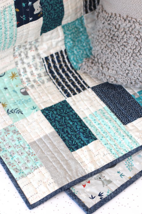 Bricks Baby Quilt Tutorial by popular quilting blog Diary of a Quilter: image of a various shades of blue bricks baby quilt draped over a crib railing.