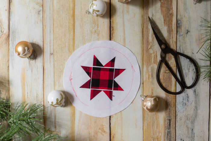 DIY Heirloom Christmas Ornament guest post by Coral + Co by popular Utah quilting blog, Diary of a Quilter: image of red and black plaid Ohio star laid on a round white piece of felt fabric.