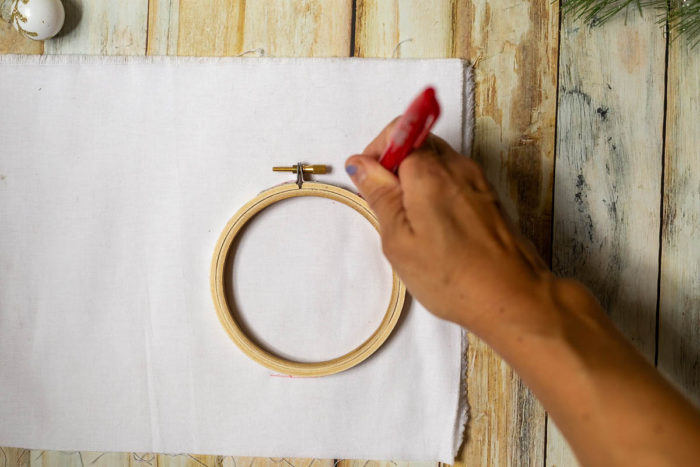 DIY Heirloom Christmas Ornament guest post by Coral + Co by popular Utah quilting blog, Diary of a Quilter: image of a woman tracing around an embroidery hoop with a red pen.