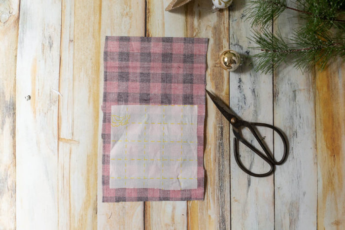 DIY Heirloom Christmas Ornament guest post by Coral + Co by popular Utah quilting blog, Diary of a Quilter: image of some sewing scissors and the backside of some black and red plaid fabric with a 4" square of Steam a Seam 2 on the lower half of the fabric.