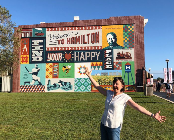 Birthday Bash at Missouri Star Quilt Company by popular quilting blog, Diary of a Quilter: image of a woman standing in front of the Welcome to Hamilton sign.