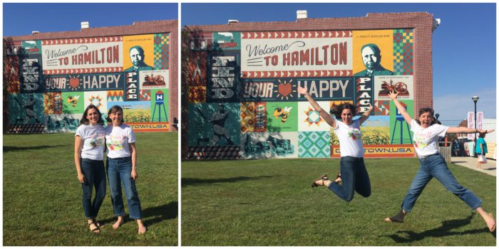 Birthday Bash at Missouri Star Quilt Company by popular quilting blog, Diary of a Quilter: image of two women jumping in front the Welcome to Hamilton sign. 