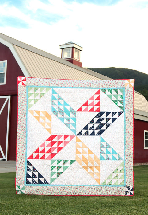 Sugarhouse Park Fabric Collection by Amy Smart by popular Utah quilting blog, Diary of a Quilter: image of a quilt made out of Sugarhouse Park fabric displayed outside in front of a red barn. 