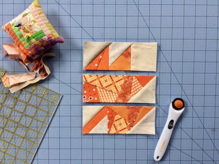 Scrappy Maple Leaf Quilt Pattern Tutorial by guest writer Leila Gardunia by popular quilting blog, Diary of a Quilter: image of scrappy maple leaf quilt blocks on a cutting board next to a rotary cutter.