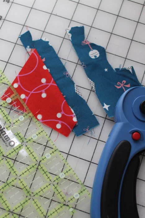 Felt Tree Ornament Tutorial by guest Stephanie of Swoodson Says by popular quilting blog, Diary of a Quilter: image of blue and red scrappy fabric on a cutting board. 