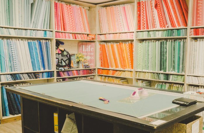 Shop Local - My Girlfriend's Quilt Shoppe + Giveaway by popular Utah quilting blog, Diary of a Quilter: image of of fabric bolts and a cutting table inside My Girlfriend's Quilt Shoppe.