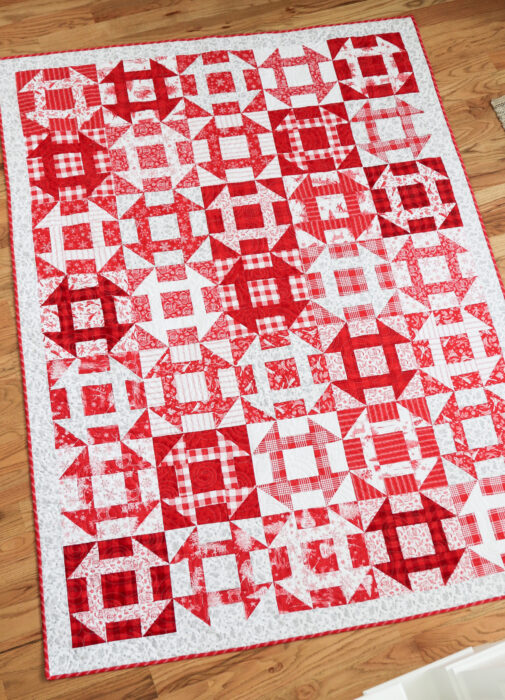 Red and white Churn Dash quilt made with Fast Churn Dash pattern by Amy Smart. Fabric is Peace on Earth by Riley Blake Designs.
