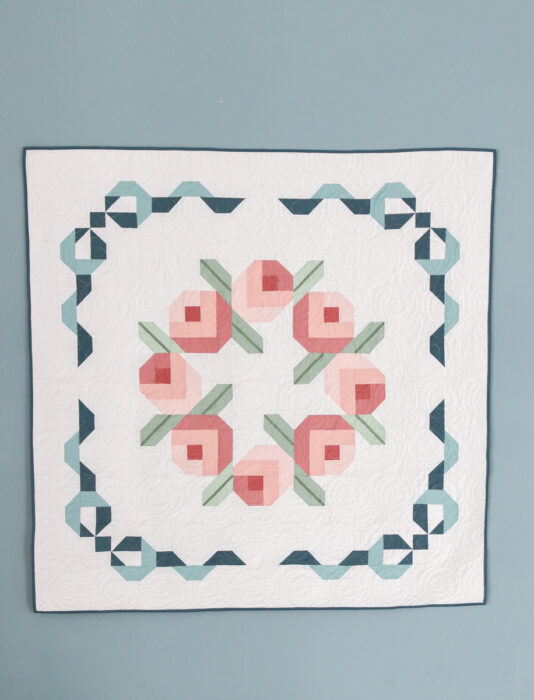 Baby-size Briarcreek Blooms laid flat; simple wreath center and narrow borders on a low-volume white.