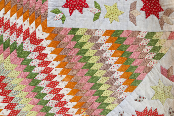 Corner block of the antique Lone Star quilt with a smaller Star of Bethlehem motif and appliquéd leafy shapes.