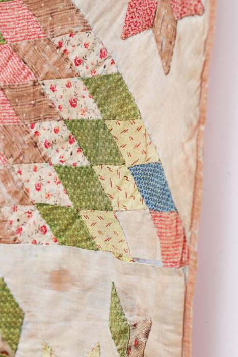 Close-up of the antique Lone Star quilt showing the tiny hand-pieced diamond patches and worn, frayed fabrics.