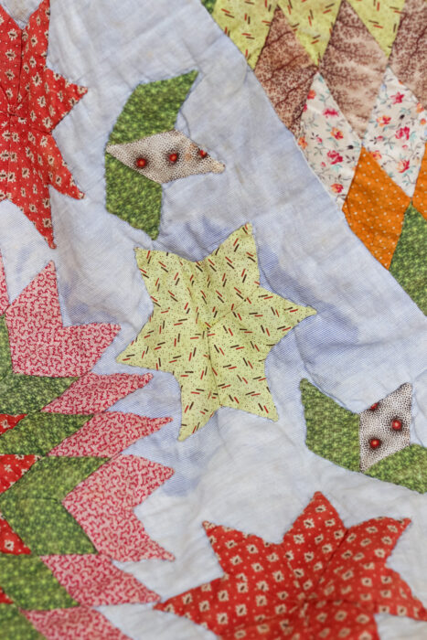 Close-up of the antique Lone Star quilt showing the tiny hand-pieced diamond patches and "vanished" or faded blues