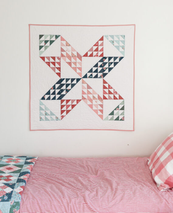Sugarhouse Star baby quilt hanging flat, crisp star points, soft pastel prints from Mary Catherine collection on tonal white print