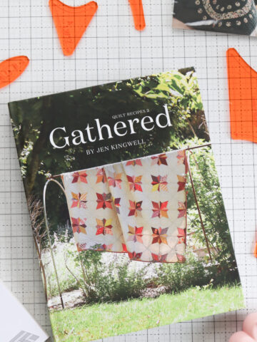 Cover of Gathered: Quilt Recipes 2 by Jen Kingwell styled with a scrappy patchwork quilt and vintage baking props