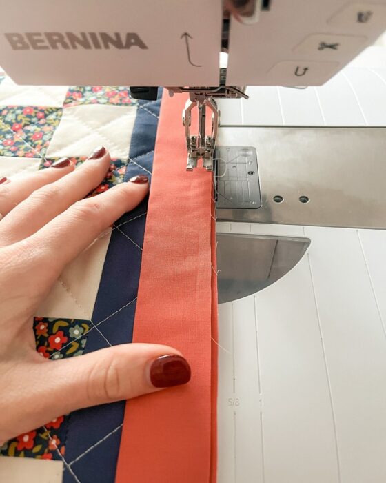Binding being attached to the quilted gameboard; corners aligned and clipped.