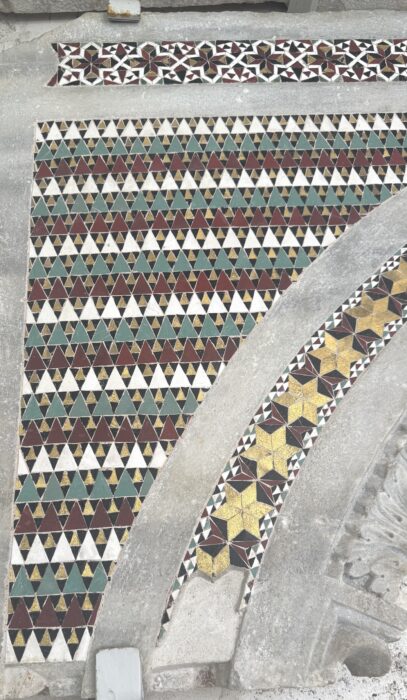 Medieval mosaic fragment featuring repeating diamonds, triangles, and three-dimensional tumbling-cube designs.
